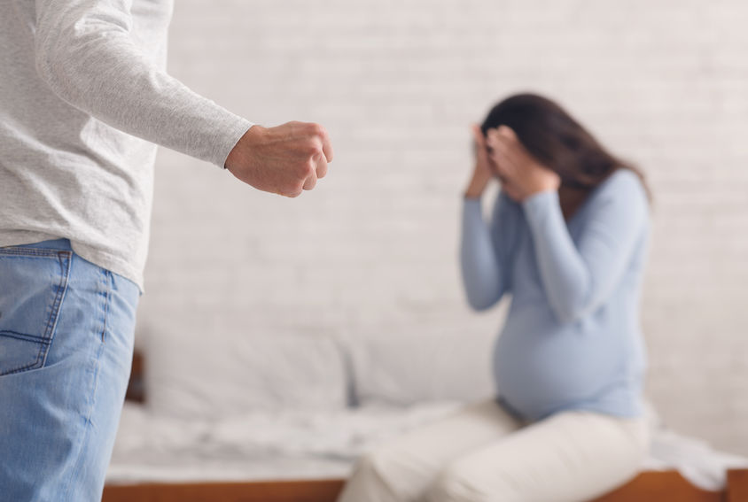 Domestic abuse. Pregnant woman suffering from home violence, selective focus on male fist.